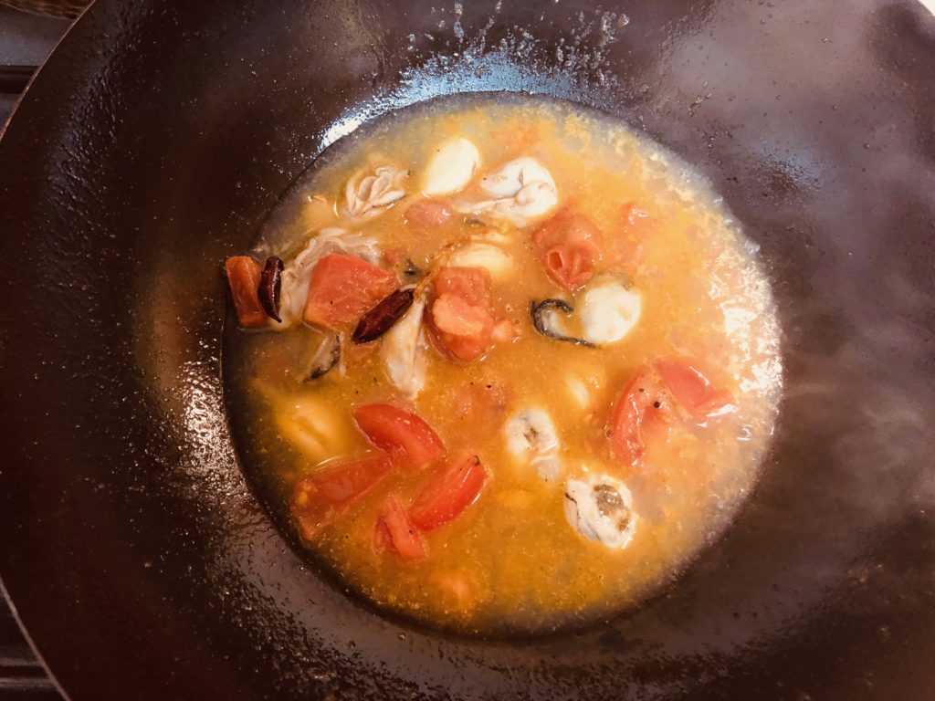 牡蠣やトマトをさっと炒め、水出汁を加え炒める
